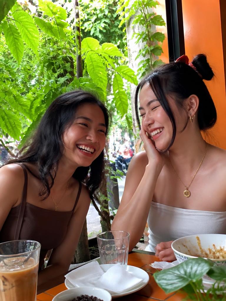 Two friends laughing together at a cafe